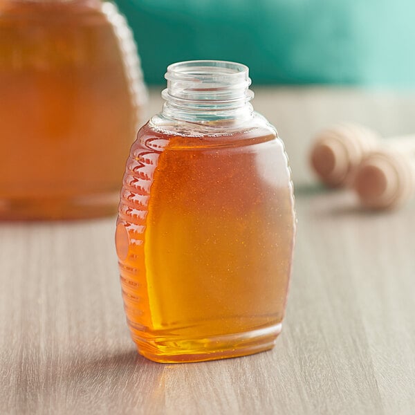 An 8 oz. Queenline PET honey jar with a clear lid on a table.