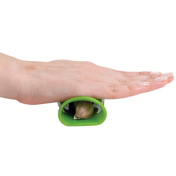 A close-up of a hand using a green and white OXO Good Grips garlic peeler.