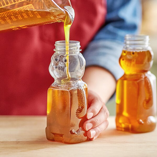 A person pouring honey into a Bear PET honey bottle.