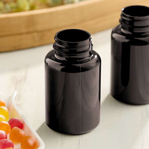 Two dark amber 175cc packer bottles next to a bowl of candy.