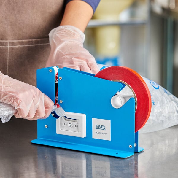 A blue Lavex bag sealing tape dispenser being used to seal a plastic bag.