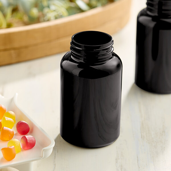Two dark amber 250cc packer bottles with black lids on a counter next to a bowl of candy.