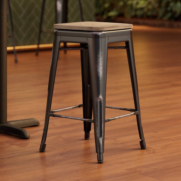 A Lancaster Table & Seating backless counter height bar stool with a gray wood seat and black metal legs.