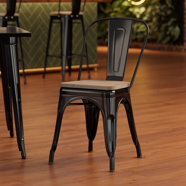 A Lancaster Table & Seating black metal chair with a gray wood seat at a table in a restaurant.