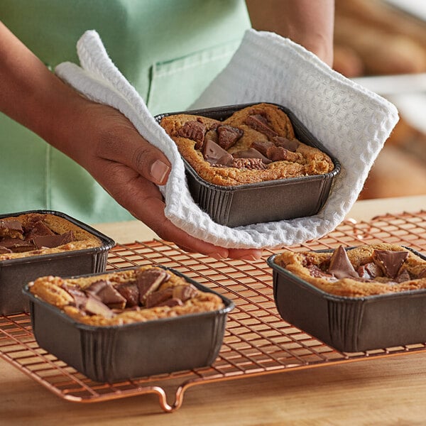 A person holding a Novacart brown paper baking mold filled with food on a tray.