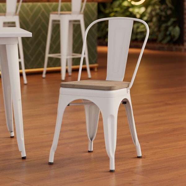 A white Lancaster Table & Seating metal chair with a gray wood seat on a table in a coffee shop.