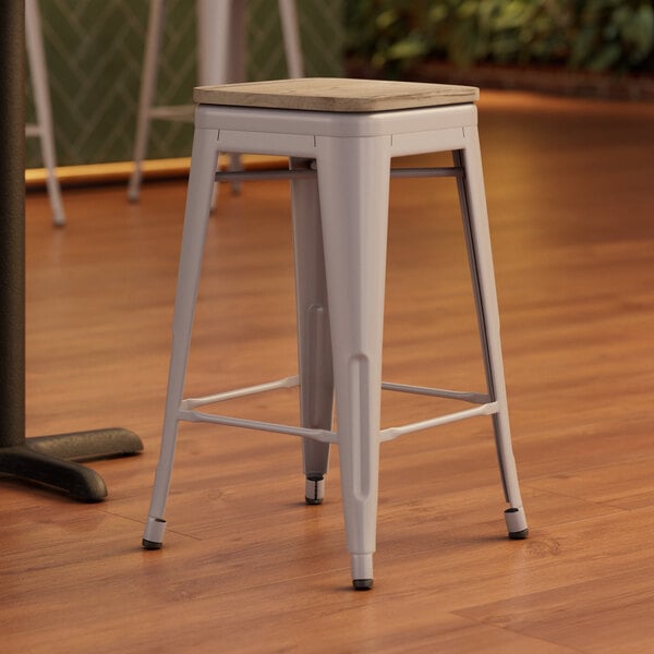 A Lancaster Table & Seating nickel gray metal backless counter height stool with a gray wood seat.