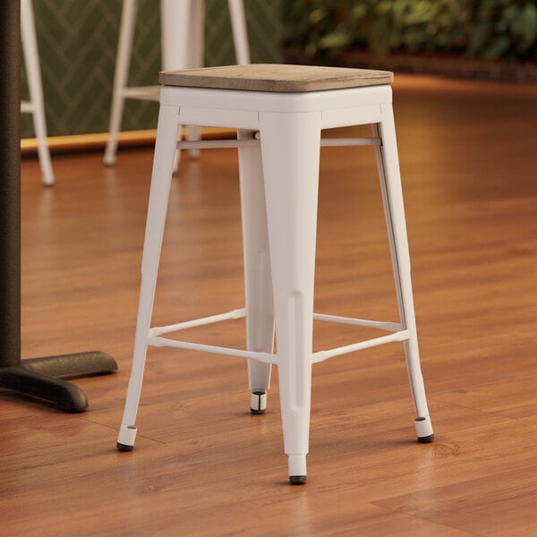 A Lancaster Table & Seating white backless counter height stool with a gray wood seat.