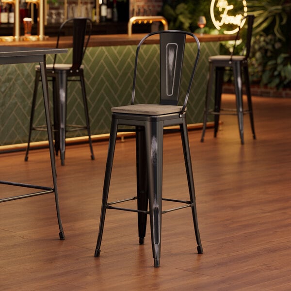 A Lancaster Table & Seating barstool with a gray wooden seat and black metal legs.