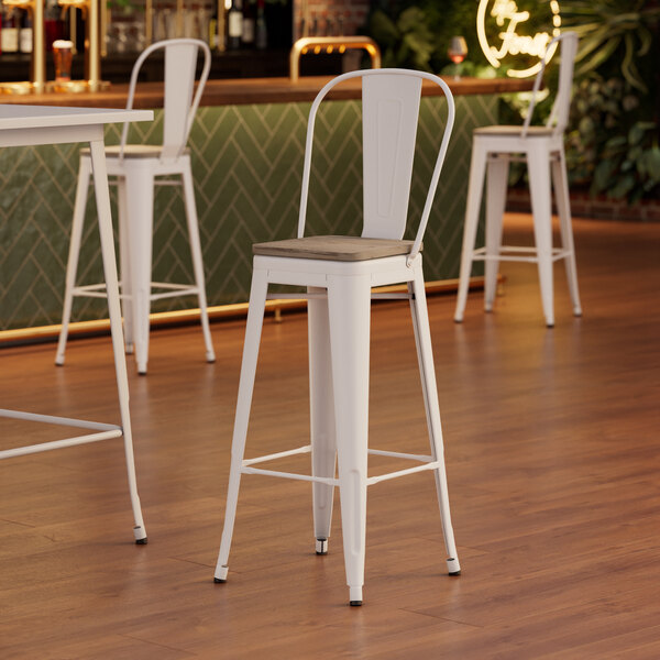 A Lancaster Table & Seating white metal barstool with a gray wood seat