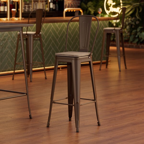 A Lancaster Table & Seating copper barstool with a wood seat on a wood floor.