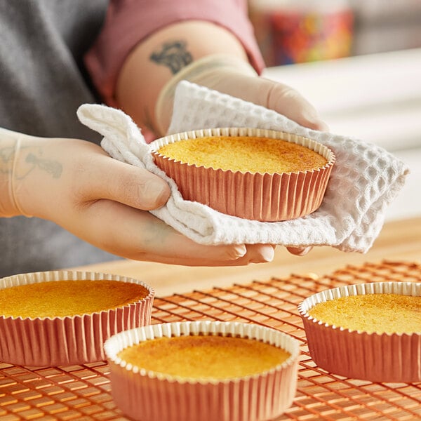 A person holding a Novacart Terra Cotta paper baking mold with a cupcake inside.