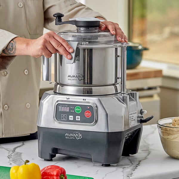 A person using an AvaMix stainless steel bowl on a motor base to make food.