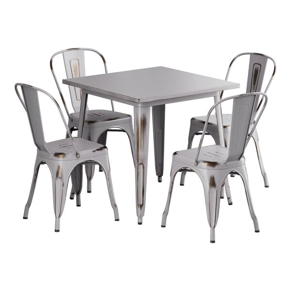 A Lancaster Table & Seating white metal table and chairs with metal legs.