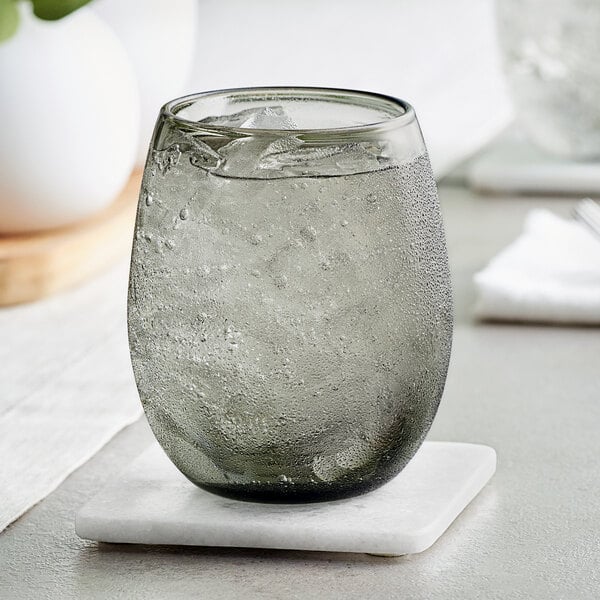 An Acopa Pangea stemless wine glass filled with ice water on a coaster.