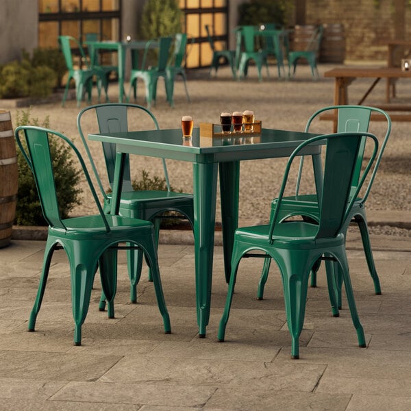 A Lancaster Table & Seating emerald green table and chairs on an outdoor patio.