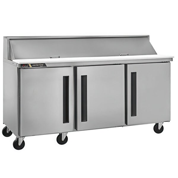 A Traulsen stainless steel refrigerated sandwich prep table with three doors on a stainless steel counter.