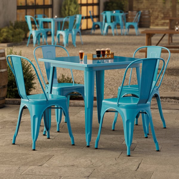 A turquoise Lancaster Table & Seating outdoor table with chairs on a patio.