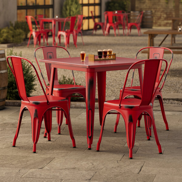 A Lancaster Table & Seating red metal table with chairs outside on a patio.