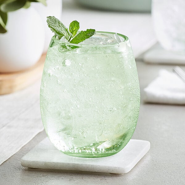 An Acopa green stemless wine glass filled with a green drink and mint leaves.