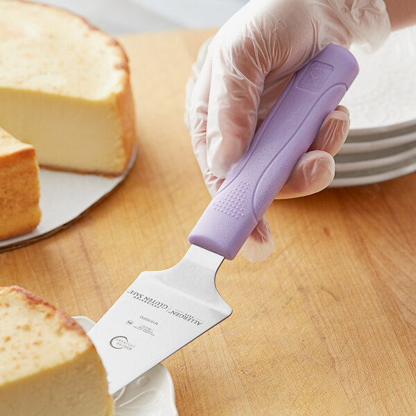 A person using a Mercer Culinary purple pie server to cut a piece of food.