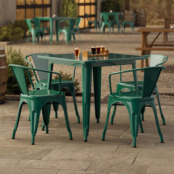 A Lancaster Table & Seating emerald green table with four chairs on a patio.