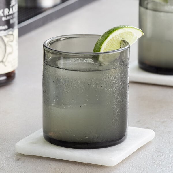 Two Acopa gray old fashioned glasses filled with whiskey and lime wedges.