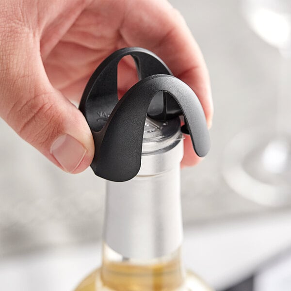 A hand holding a Vacu Vin black foil cutter over a wine bottle.