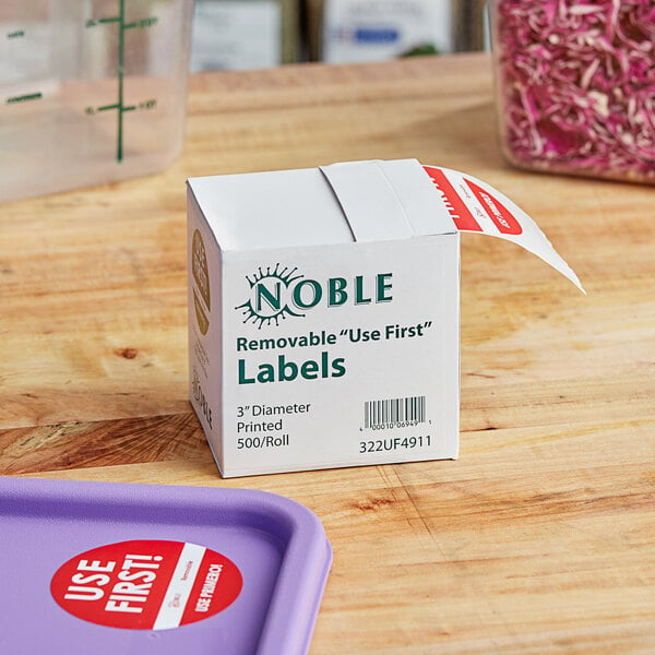 A white Noble Products box with green text on a table next to a purple tray of food.