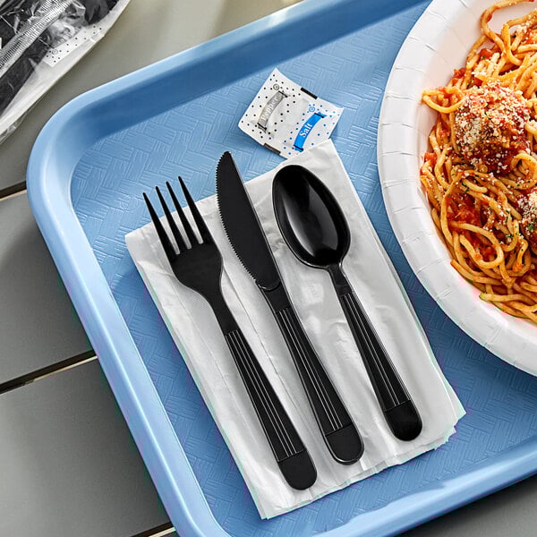 A tray with a bowl of spaghetti and black utensils including a fork and knife on a white napkin.