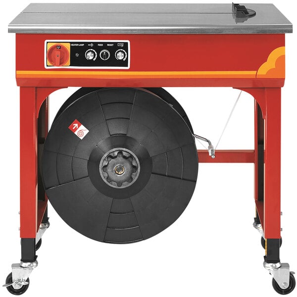 a red and silver machine with a round black object on wheels