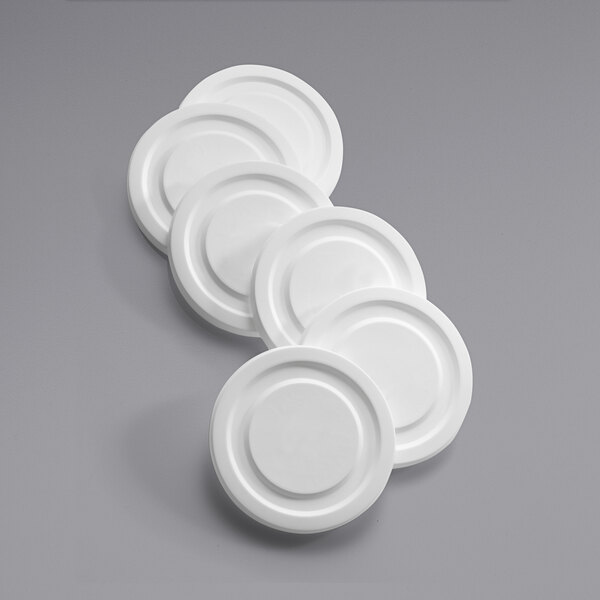 A group of white plastic Arcoroc lids.