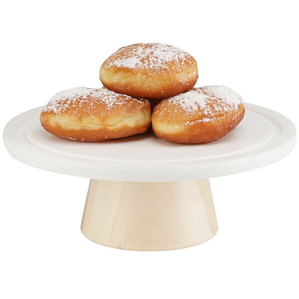 A Cal-Mil maple wood cake stand with doughnuts on it.