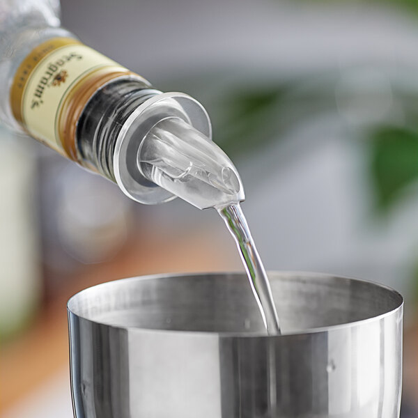 A person using a Choice clear liquor pourer to pour liquid into a metal cup.