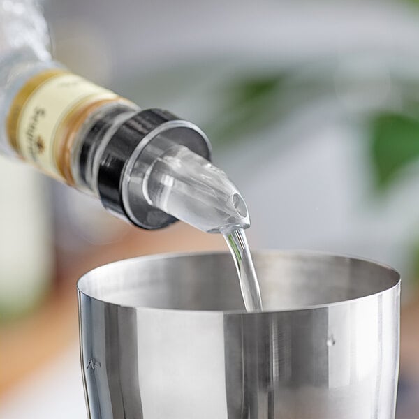 A person using a silver Choice Liquor Pourer to pour liquid into a metal cup.