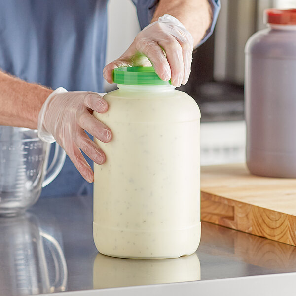 A person in gloves pouring white liquid from a white Choice gallon container.