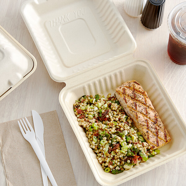 A Footprint Bagasse take-out container filled with salmon and salad on a table.