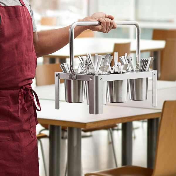 A man holding a Choice stainless steel flatware carrier filled with utensils.