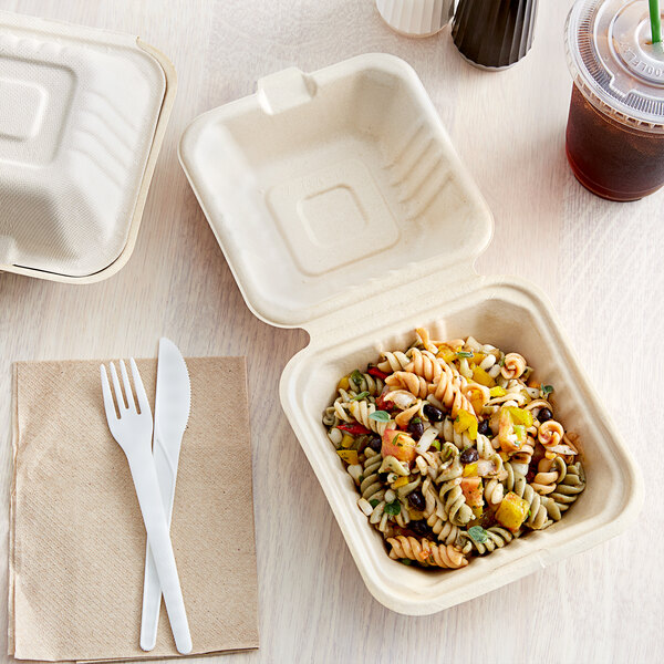 A Footprint Bagasse take-out container with pasta and vegetables on a fabric surface.