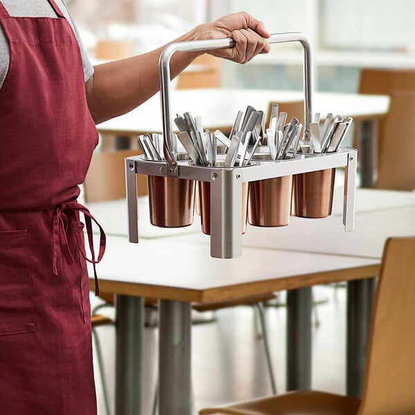 A man holding a Choice stainless steel flatware carrier with utensils inside.