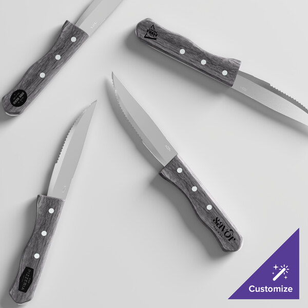 A set of four steak knives with serrated blades and gray pakkawood handles, arranged on a white surface.