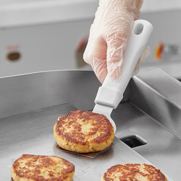 A person using a Choice mini turner to put food on a pan.