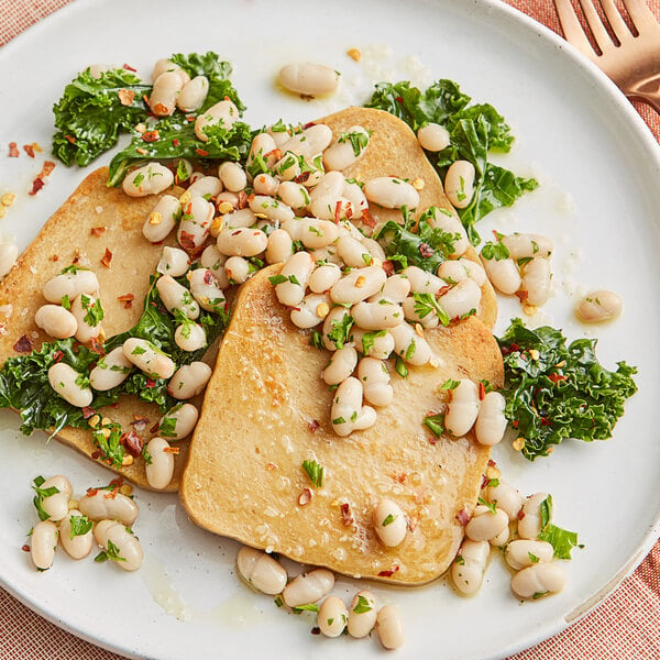 a plate of food with white beans and green leaves