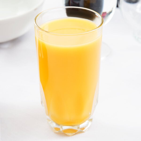 An Arcoroc Artic beverage glass filled with orange juice on a table.