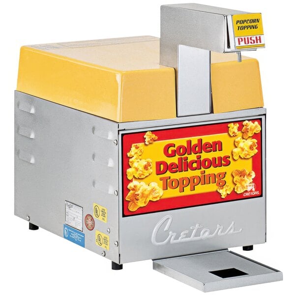 A Cretors countertop butter dispenser with a yellow top and a sign reading "popcorn" on it.