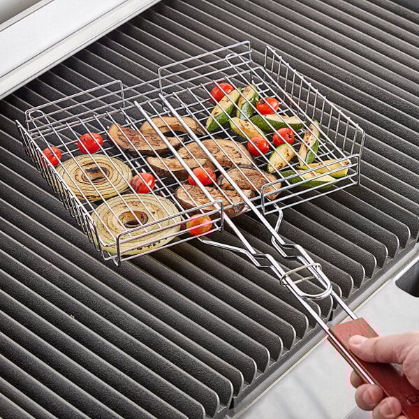 A person grilling vegetables in an Outset chrome grill basket.