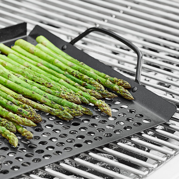 An Outset non-stick grill tray with asparagus cooking on it.