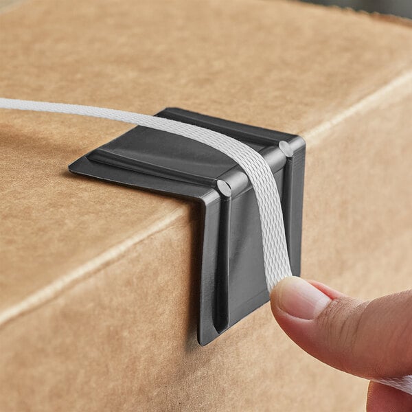 A person holding a black plastic strapping edge protector box.