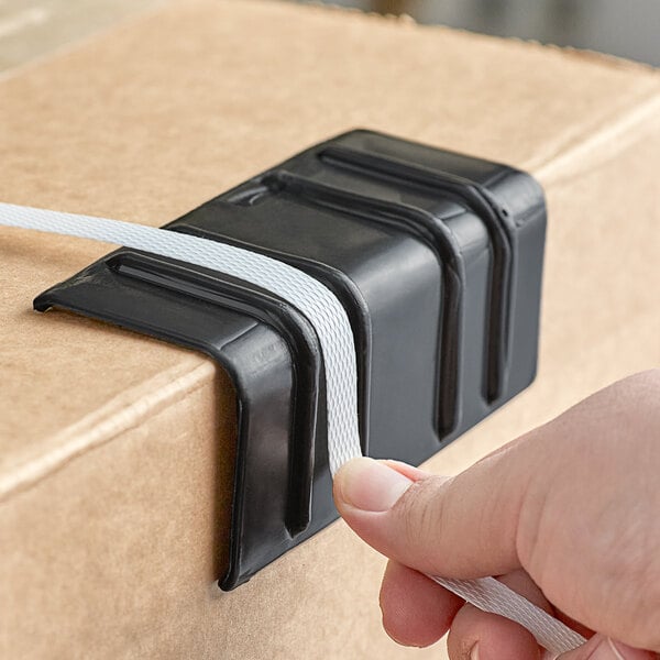 A person holding a black box of black strapping edge protectors with white labels.