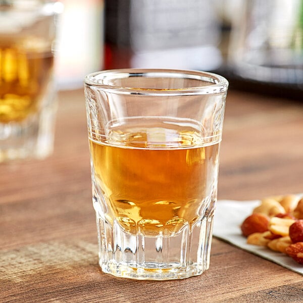 An Acopa fluted shot glass filled with liquid on a table.